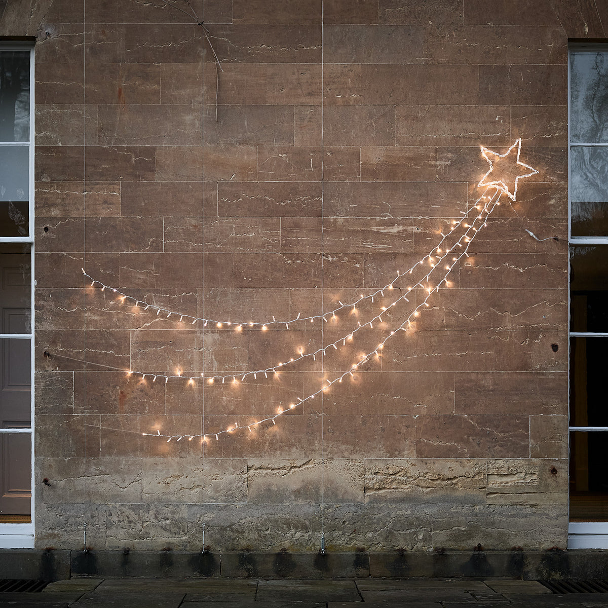 Bicolor LED Sternschnuppe mit ausgeschalteten Lichtsträngen an heller Wand