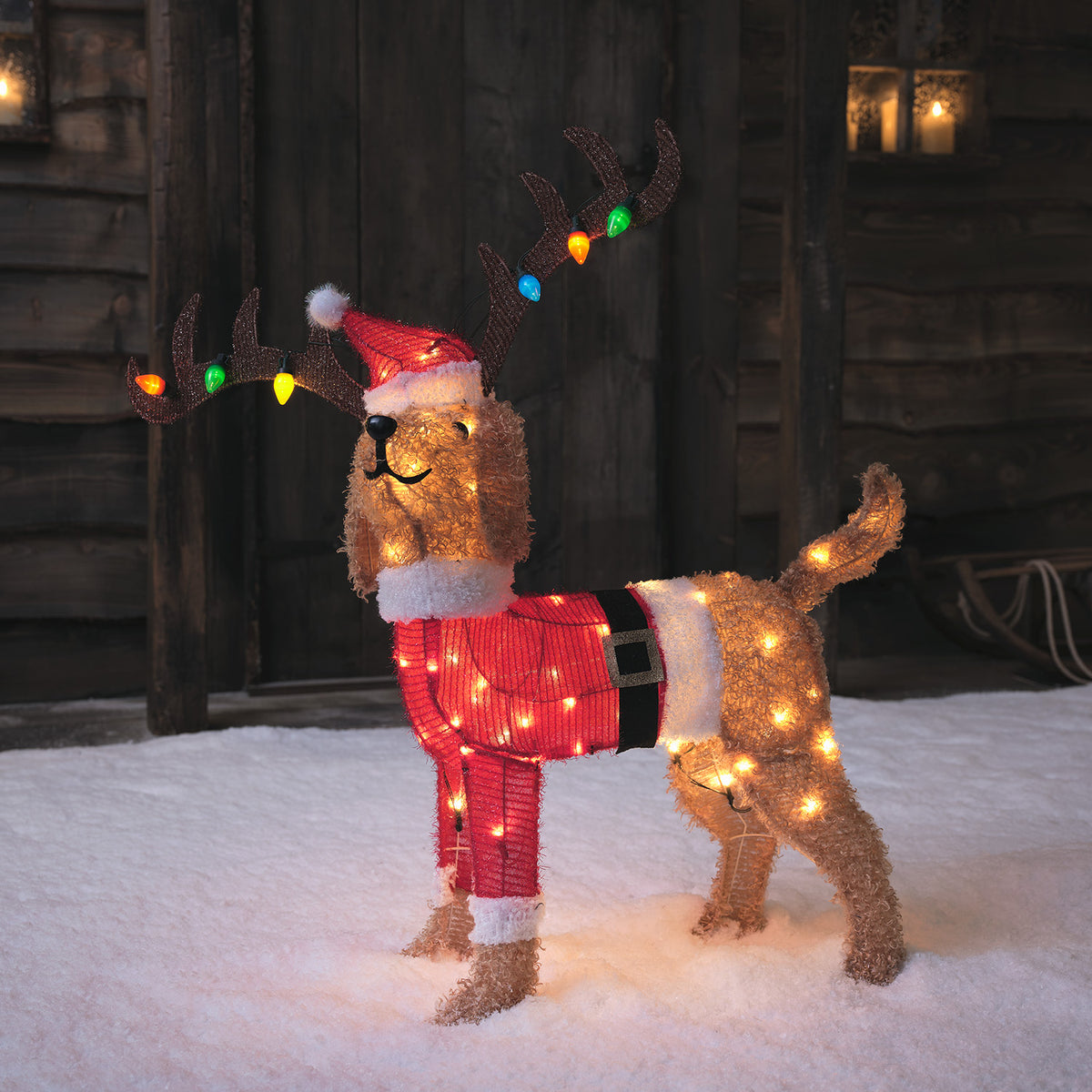 LED Weihnachtsfigur Hund mit Santa-Kostüm und buntem Hirschgeweih im Schnee