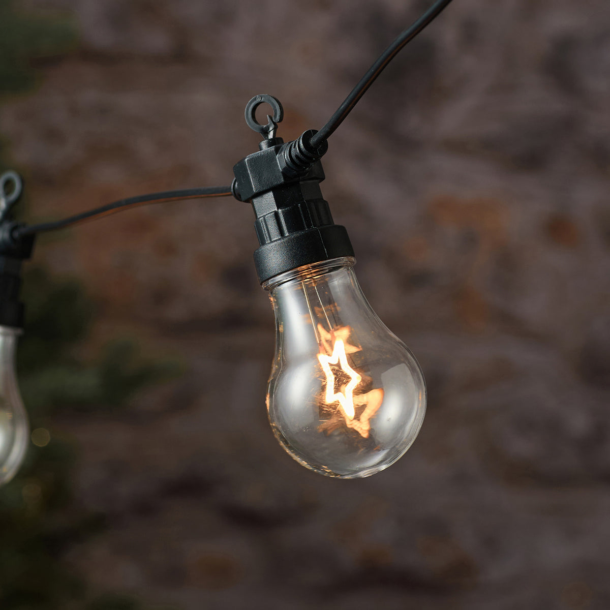 Detailaufnahme einer LED-Glühbirne mit leuchtendem Sternfilament an schwarzer Fassung