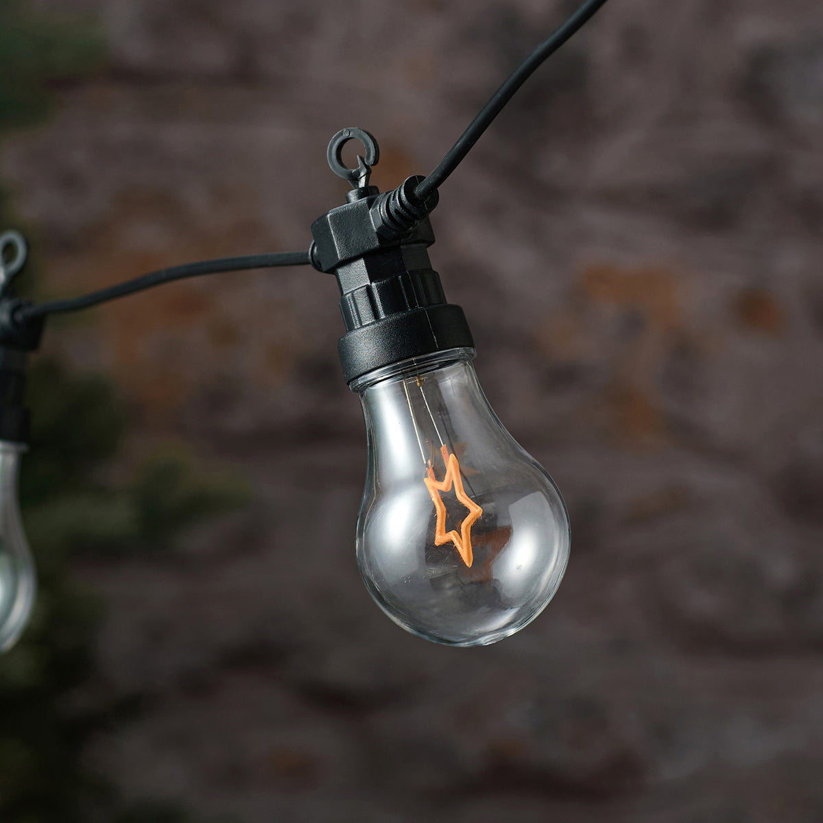 Nahaufnahme einer LED-Glühbirne mit warmweiß leuchtendem Sternfilament an schwarzer Fassung