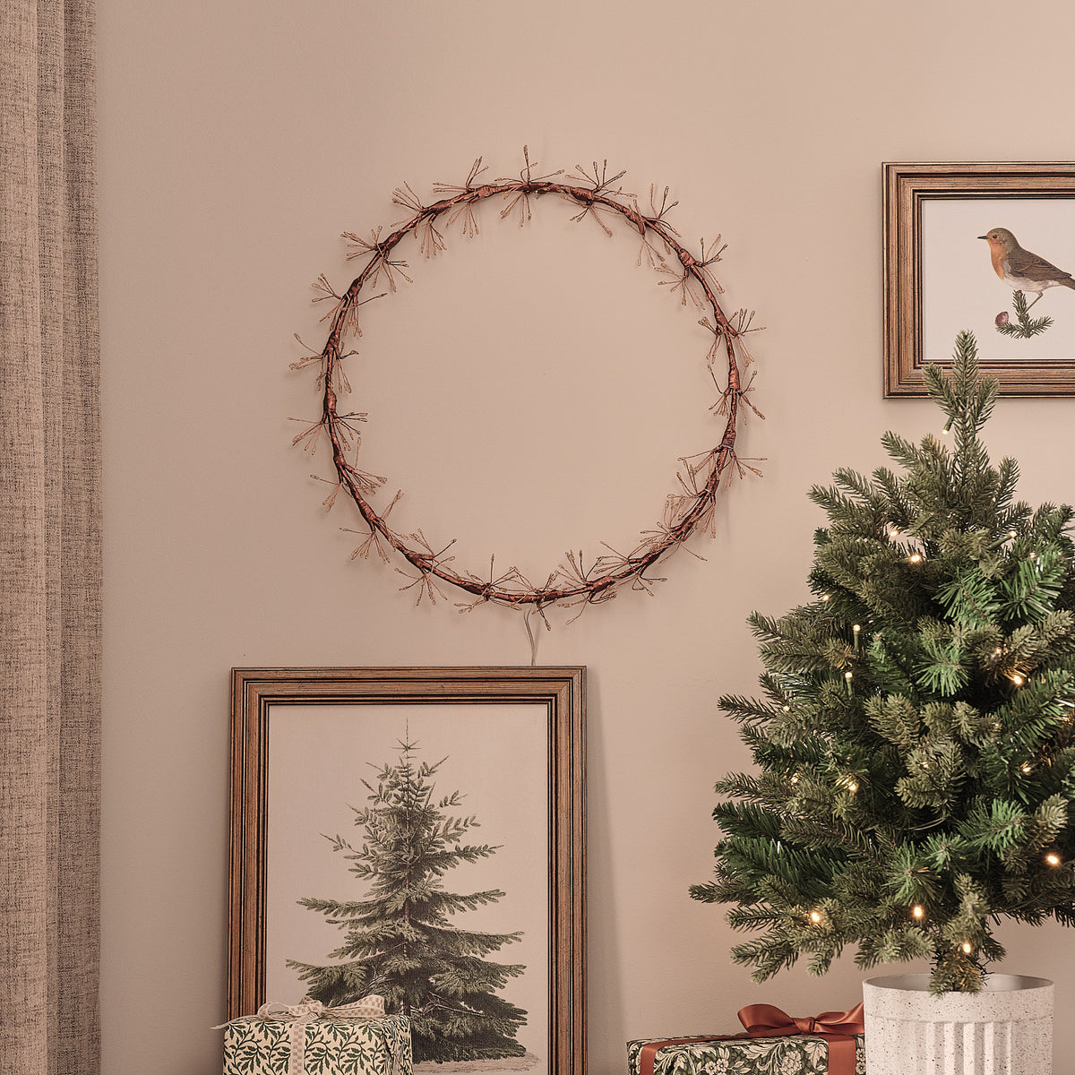 LED-Starburst-Kranz außen ohne Beleuchtung an Wand über Weihnachtsbaum mit goldfarbenem Ring