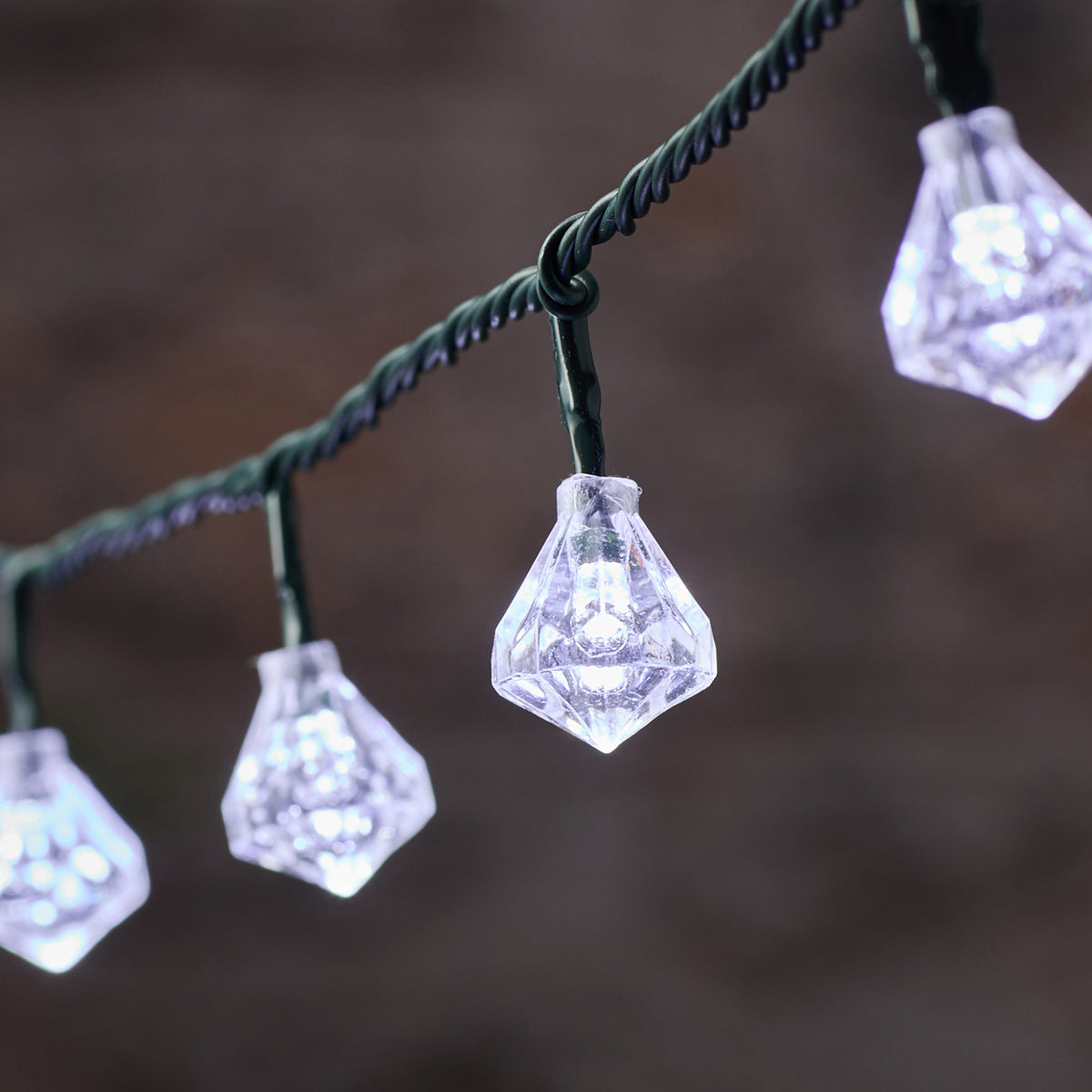 Nahaufnahme einer weißen LED mit facettierter Diamantkappe an grünem Kabel