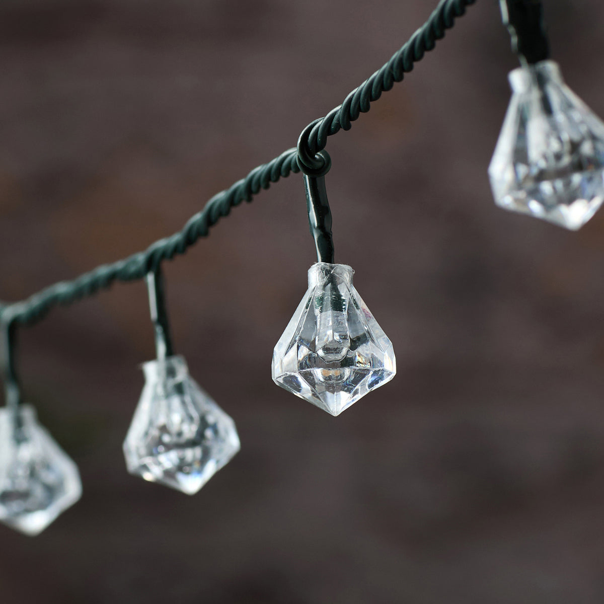 Nahaufnahme einer weißen LED mit facettierter Diamantkappe an grünem Kabel