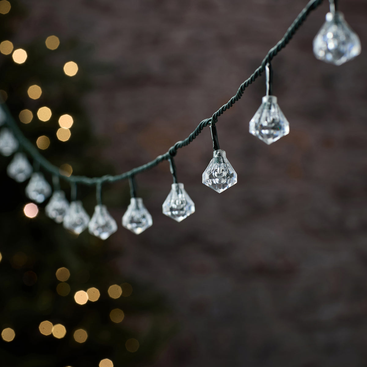 LED-Lichterkette mit klaren, unbeleuchteten facettierten Diamant-Kappen an grünem Kabel