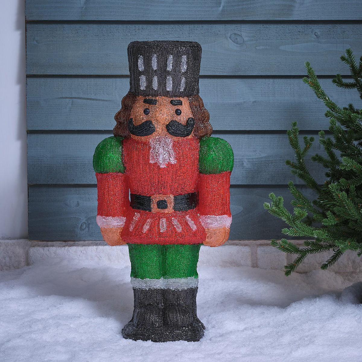 LED-Nussknacker aus Acryl mit rotem Mantel und schwarzem Gürtel stehend im Schnee ohne Beleuchtung