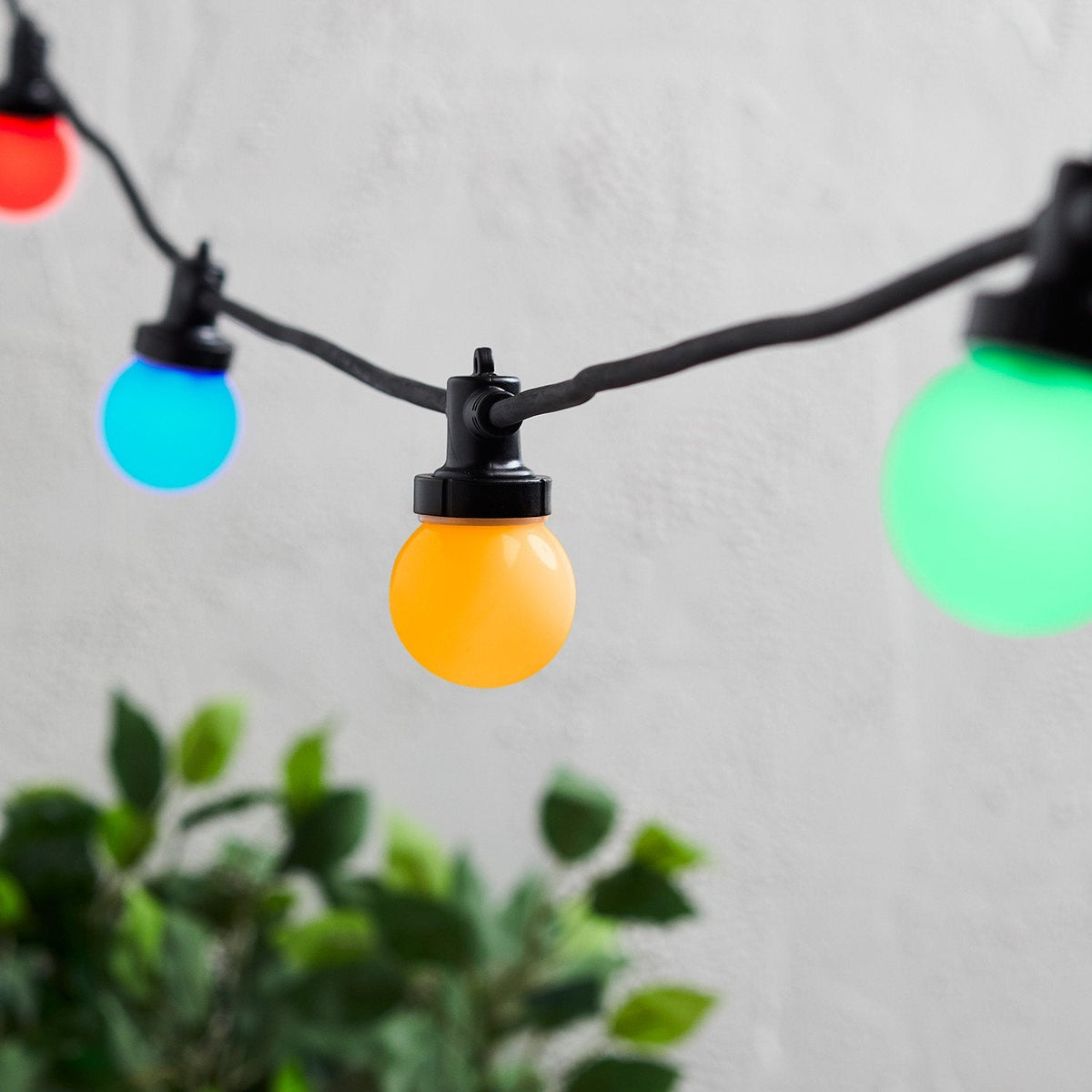 Bunte Party-Lichterkette mit IP67-Steckverbindern an schwarzem Kabel vor weißer Wand