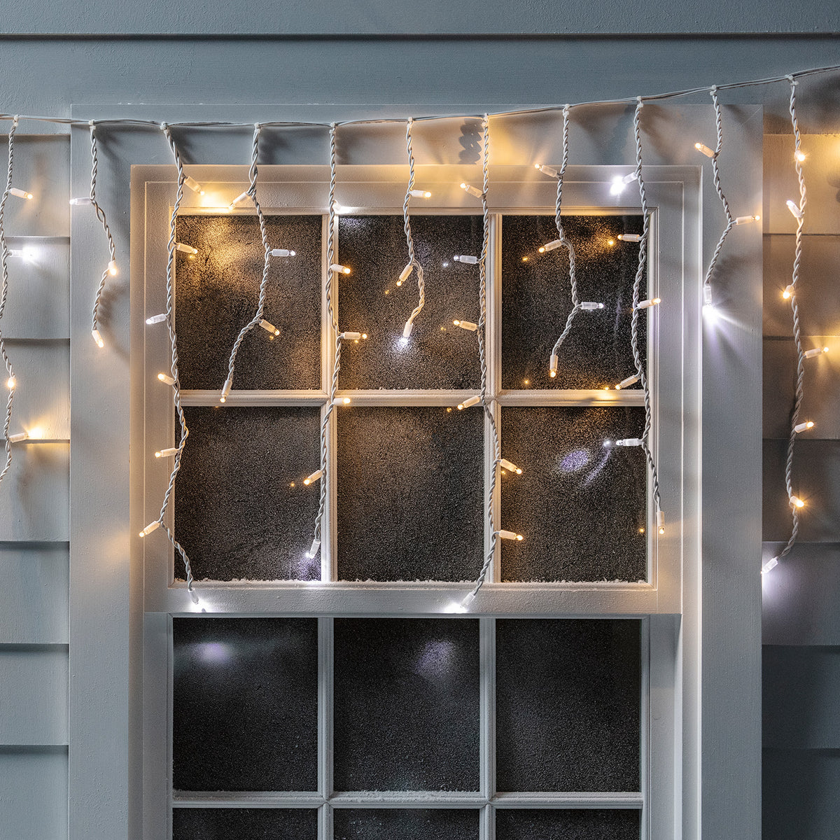 Eiszapfen-Lichterkette mit weißen und warmweißen LEDs an einem Fenster im Außenbereich