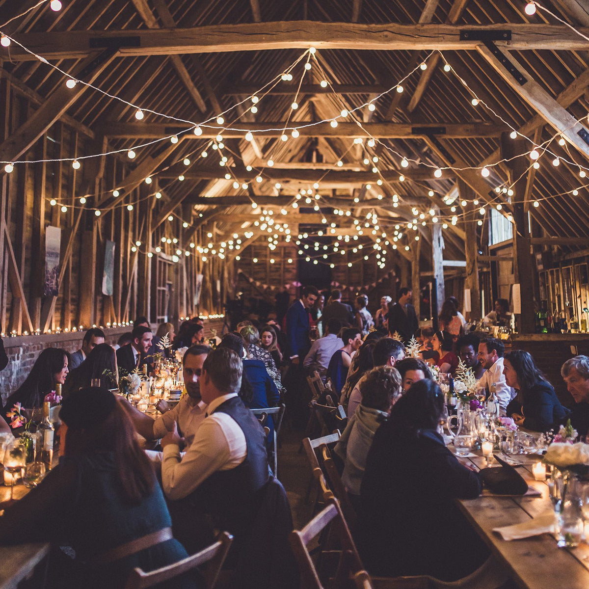 Party mit vielen Gästen in Scheune, beleuchtet mit warmweißen Lichterketten