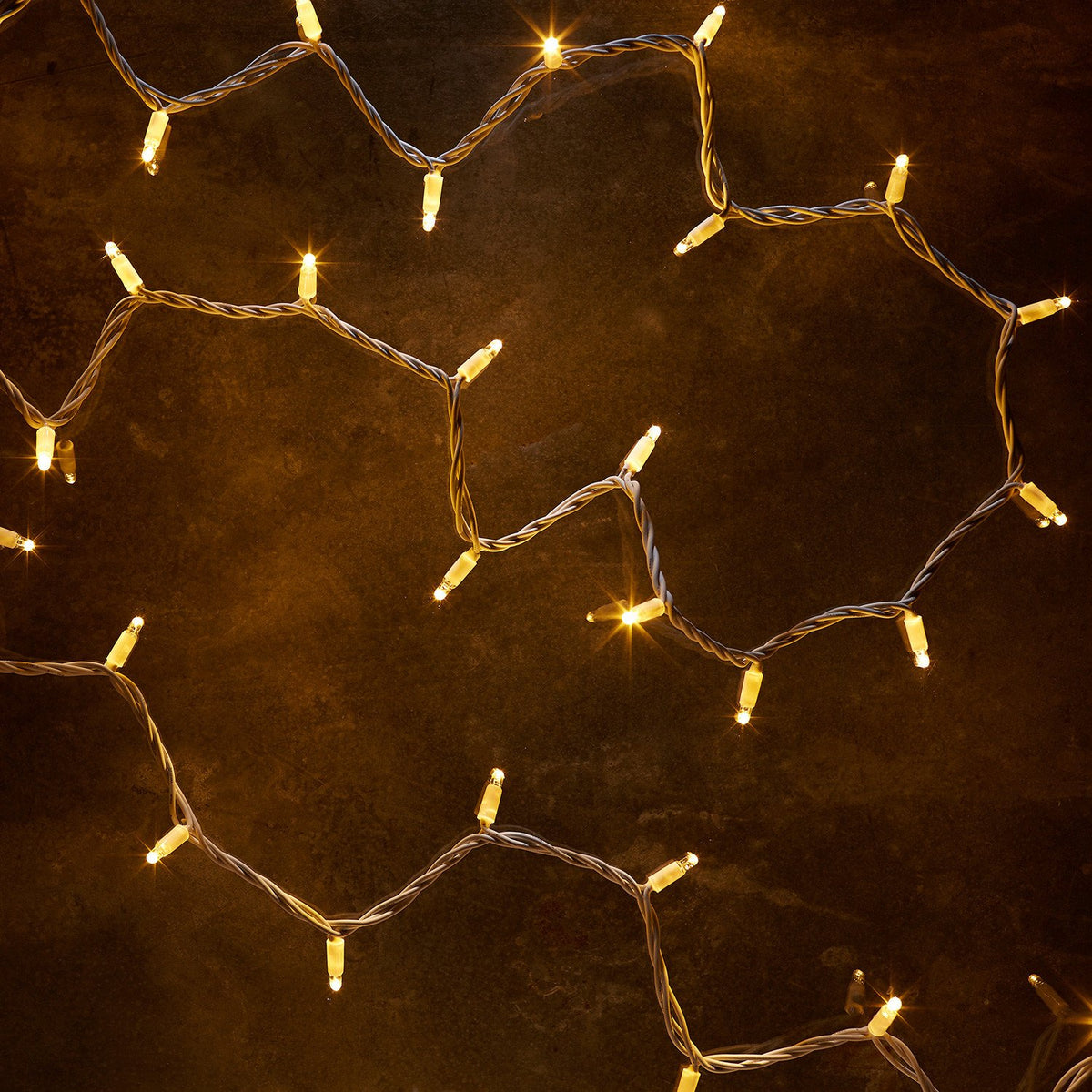 Nahaufnahme der warmweißen LED-Lichterkette mit weißem Kabel auf dunklem Untergrund