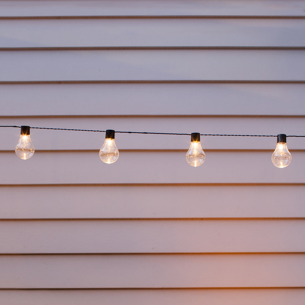 Nahaufnahme der warmweißen LED-Kugeln der Solar Party Lichterkette vor weißer Wand
