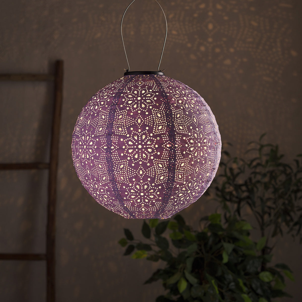 Nahaufnahme eines lila Tyvek Solar Lampions mit filigranem Blumenmuster und warmweißem Licht.