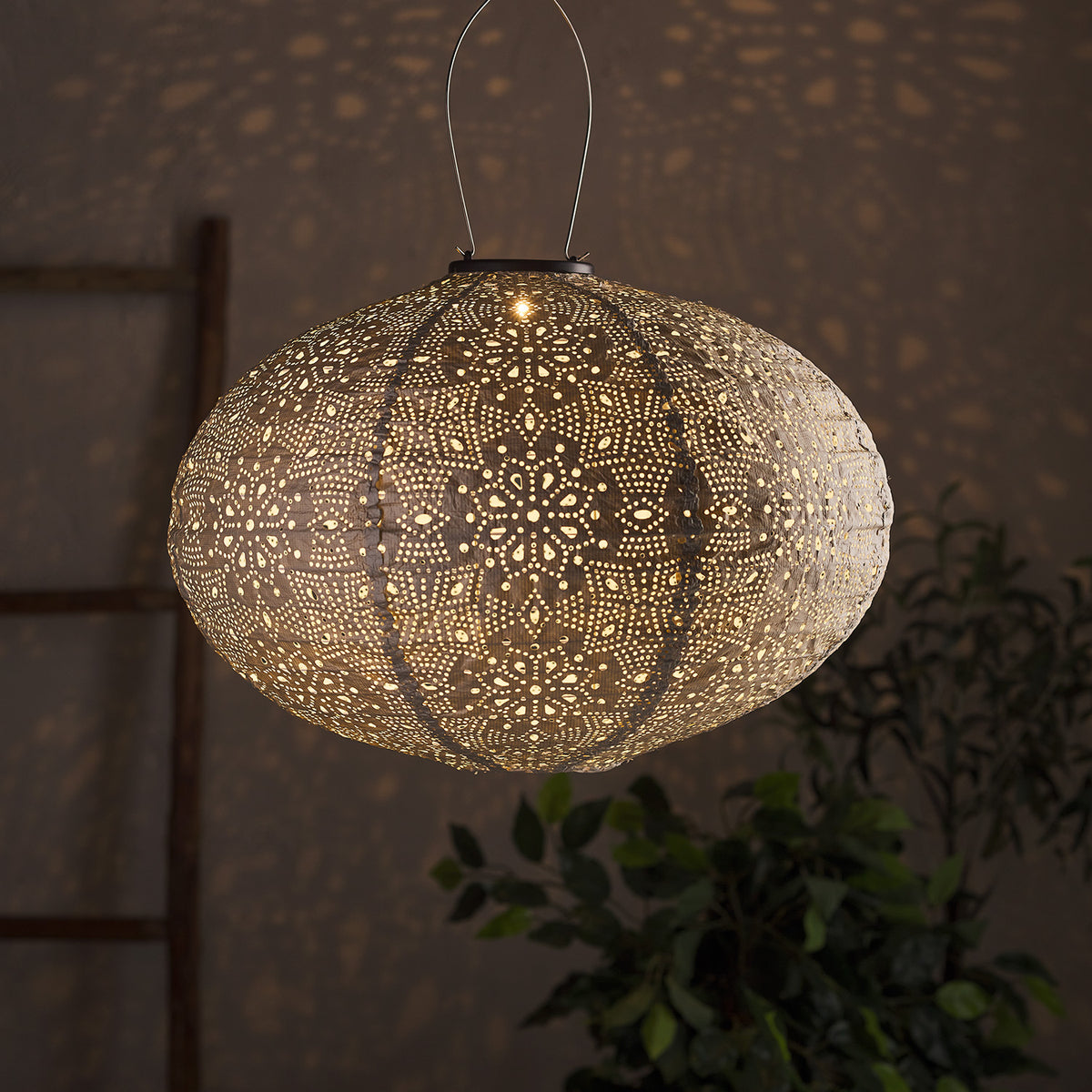 Beleuchteter ovaler weißer Tyvek Solar Lampion mit floralem Muster vor dunklem Hintergrund.