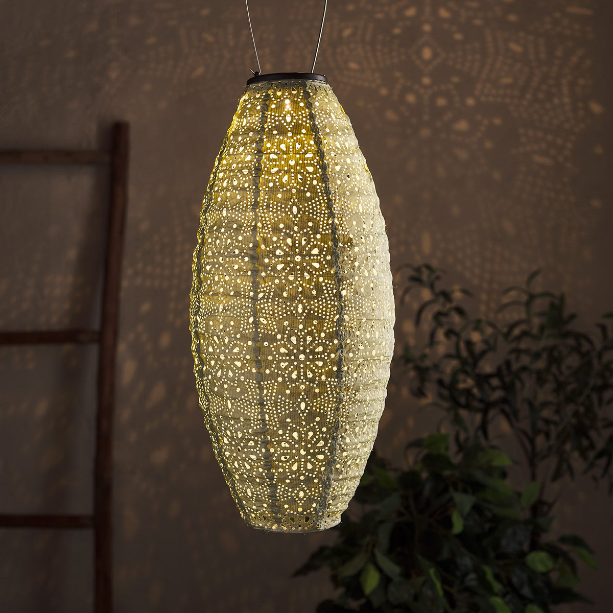 Beleuchteter weißer ovaler Tyvek Solar Lampion mit Blumenmuster und warmweißem Licht vor dunklem Hintergrund.