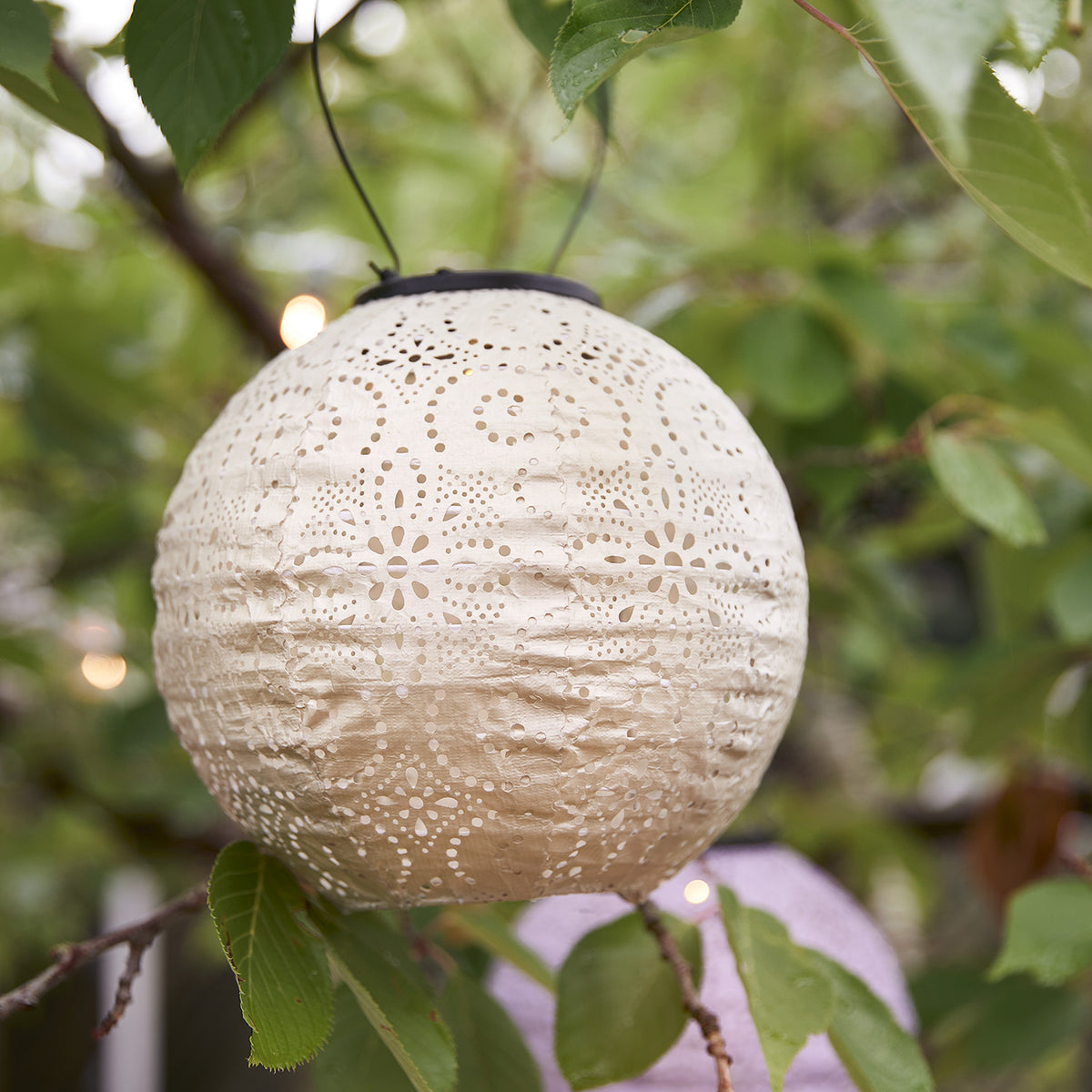 Nahaufnahme eines weißen Tyvek Solar Lampions mit Lochmuster, der an einem Baum hängt