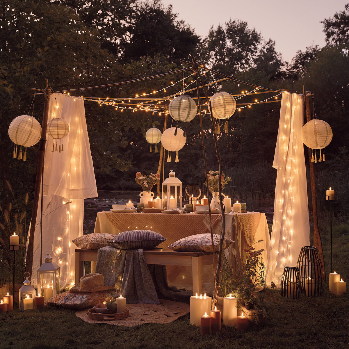 Solar-Lampion und Lichterketten schmücken einen gedeckten Gartentisch im Abendlicht