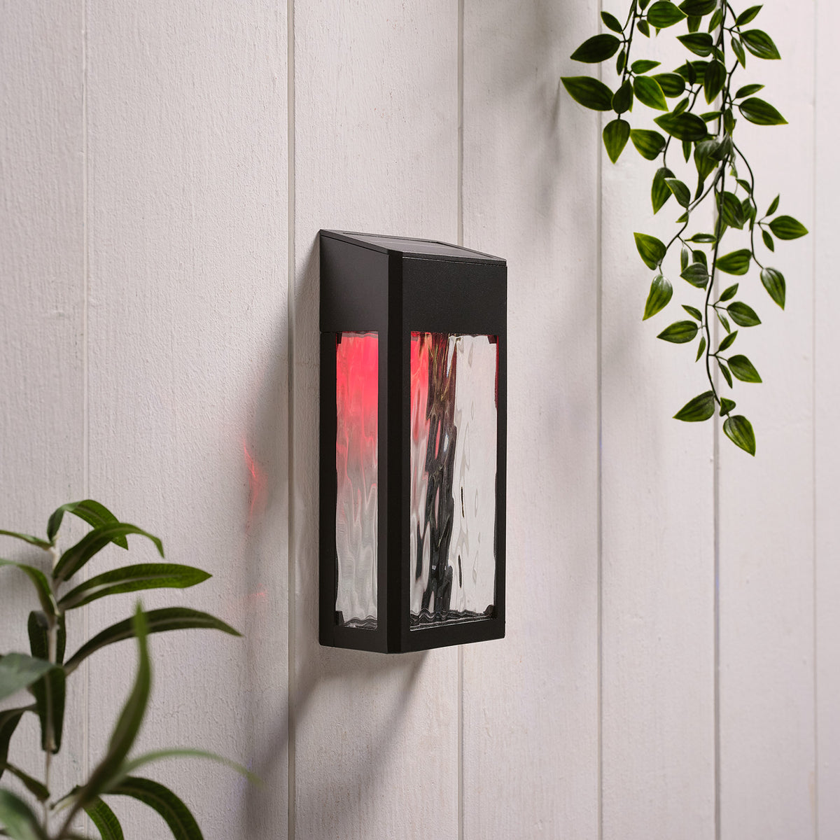 Solar-Wandleuchte mit rotem Licht und strukturierter Glasfront an weißer Wand