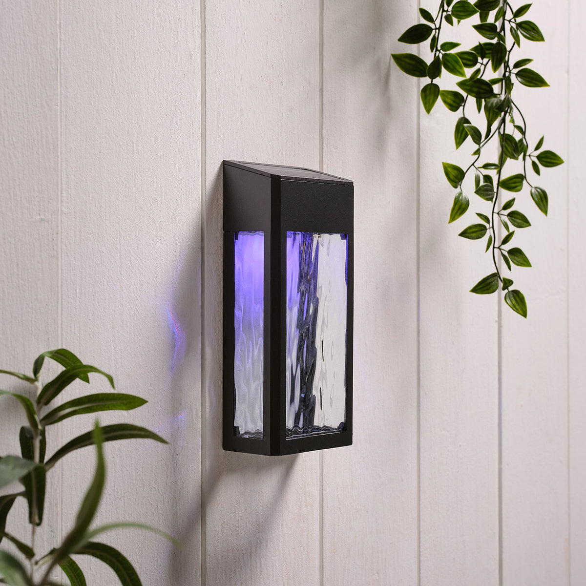 Solar-Wandleuchte mit grünem Licht und strukturierter Glasfront an weißer Wand