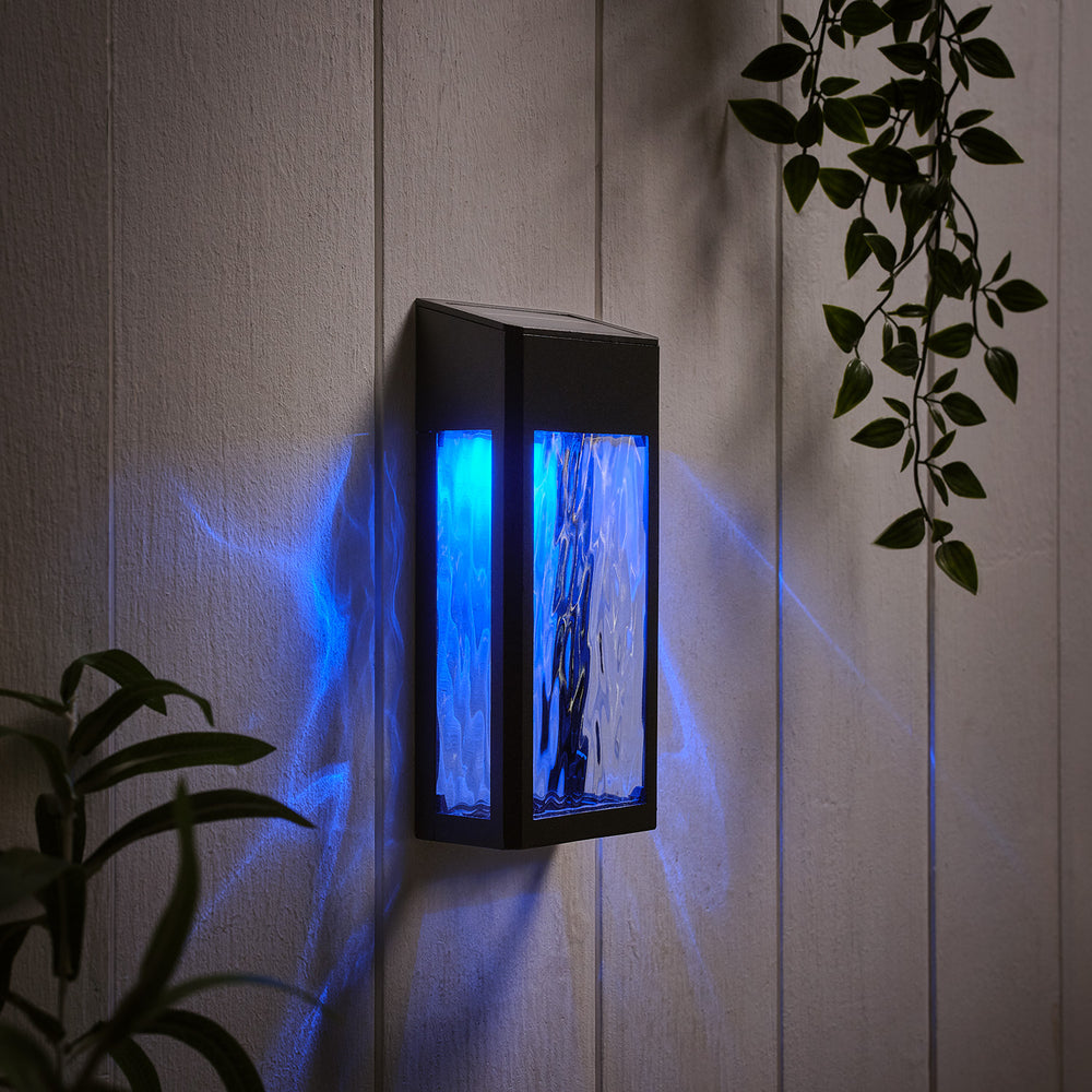 Solar-Wandleuchte mit blauem Licht und strukturierter Glasfront an weißer Wand