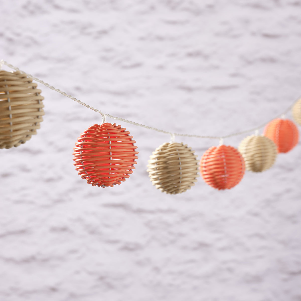 LED Solar Lichterkette mit bunten Rattankugeln in Orange und Beige auf hellem Hintergrund