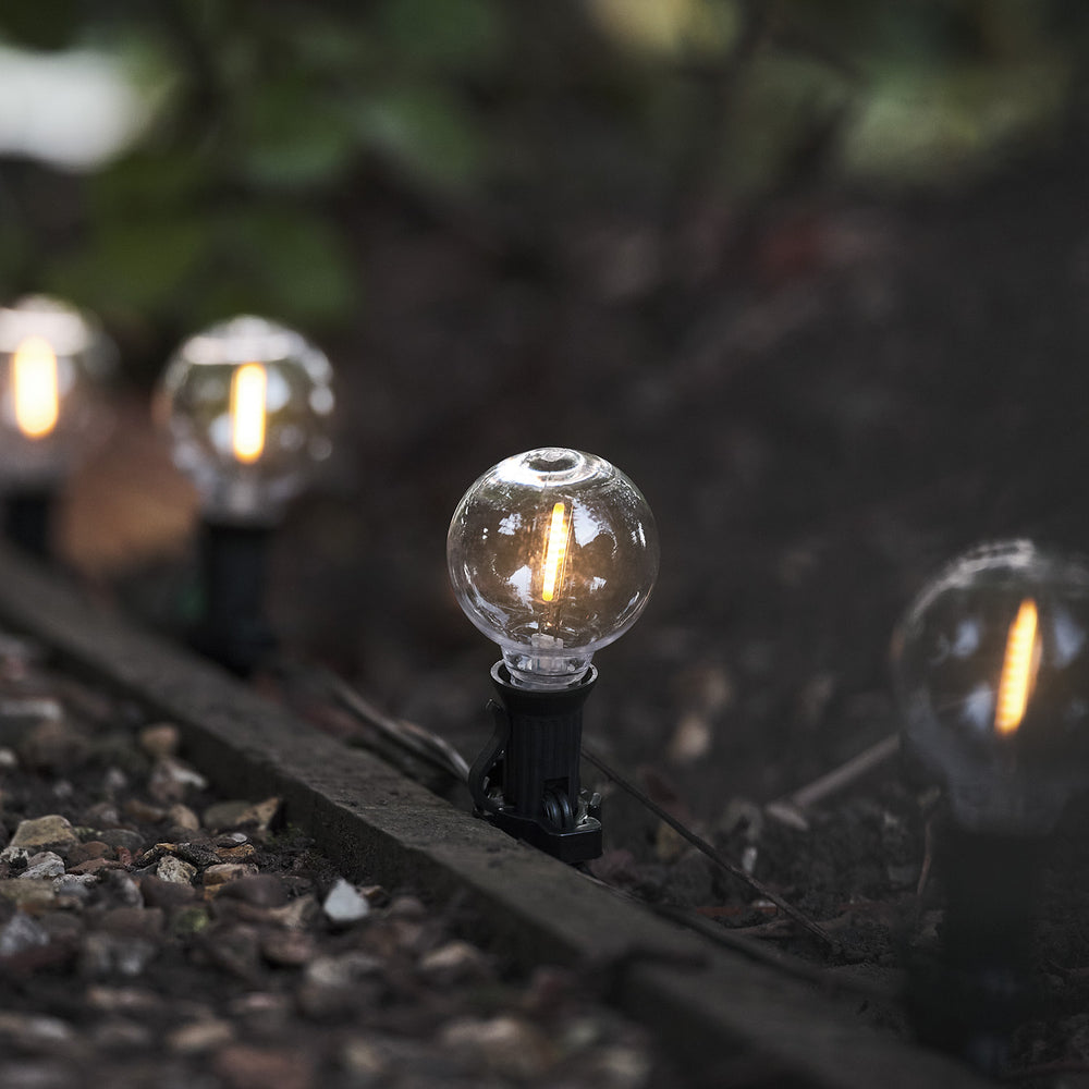 Nahaufnahme einer leuchtenden LED-Glaskugel der Solar-Lichterkette im Garten