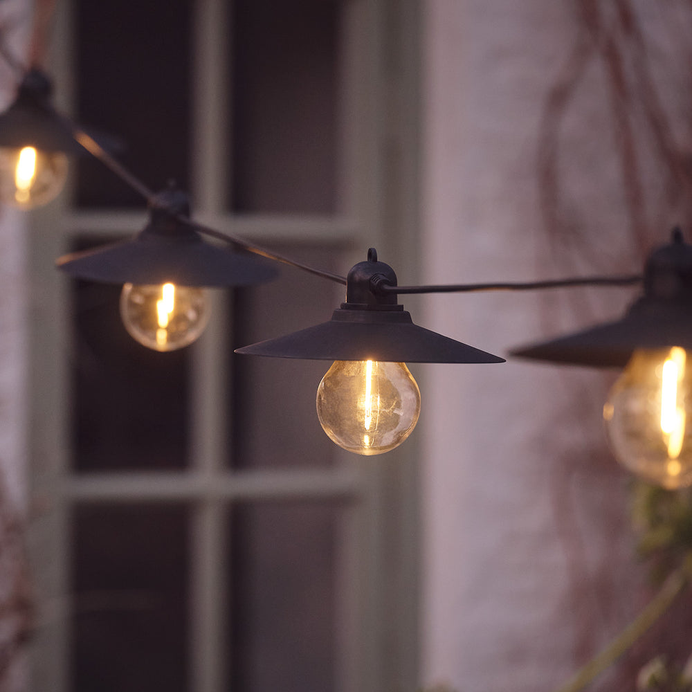 Nahaufnahme einer warmweißen LED-Glühbirne mit schwarzem Retro-Lampenschirm an einer Lichterkette