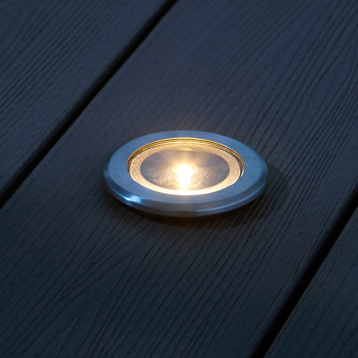 Nahaufnahme eines Solar-Terrassenstrahlers mit LED und silbernem Rahmen im Rasen