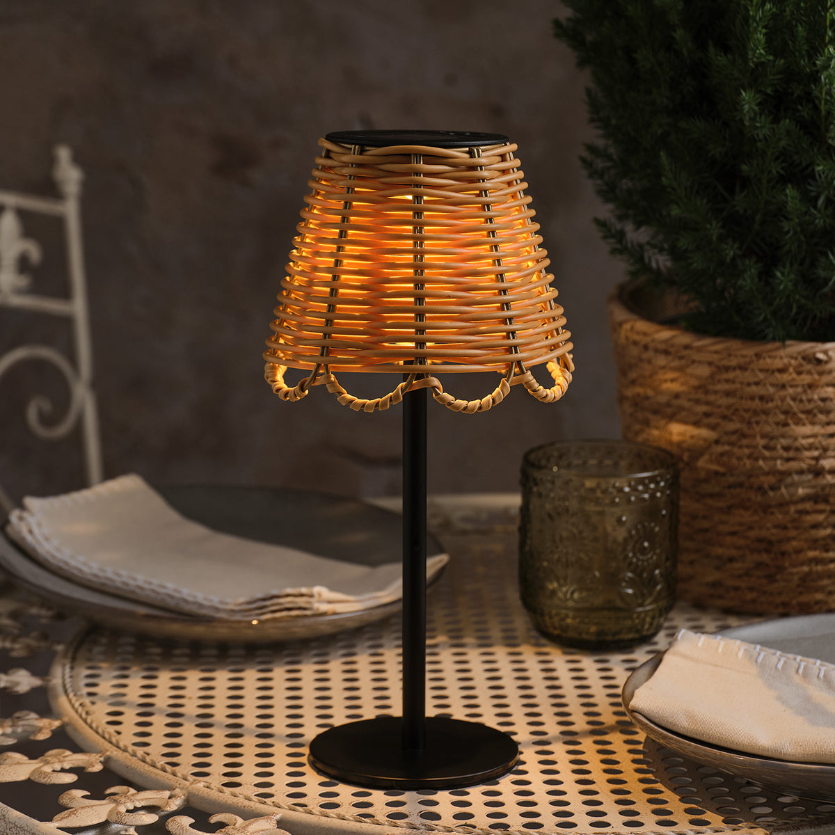 Solar-Tischlampe mit warmweißem Licht auf Metalltisch neben Serviette und Glas