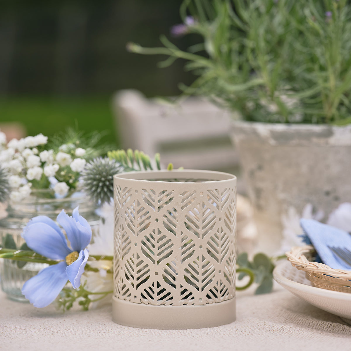 Unbeleuchtete Solarlaterne mit Blattmuster auf gedecktem Gartentisch mit Blumen