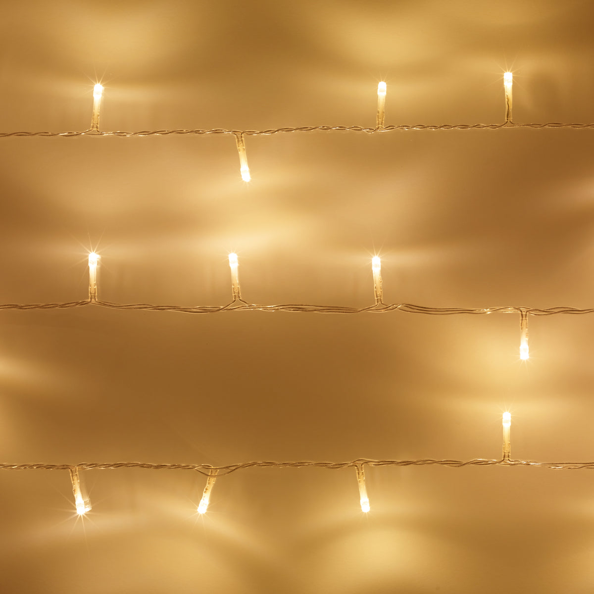 Nahaufnahme einer warmweißen LED-Lichterkette mit transparentem Kabel an Wand