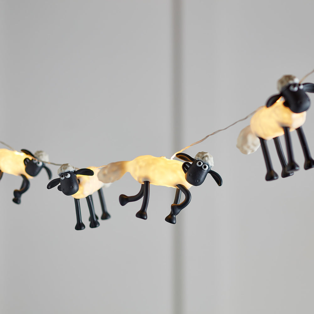 Lichterkette mit mehreren leuchtenden Shaun the Sheep Figuren vor grauem Hintergrund