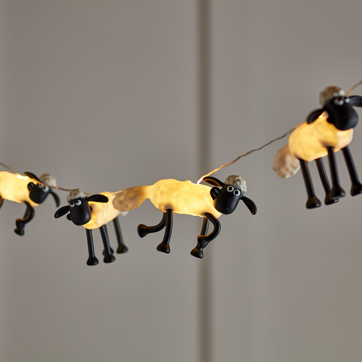 Leuchtende Shaun the Sheep Figuren der Lichterkette mit warmweißen LEDs vor grauem Hintergrund