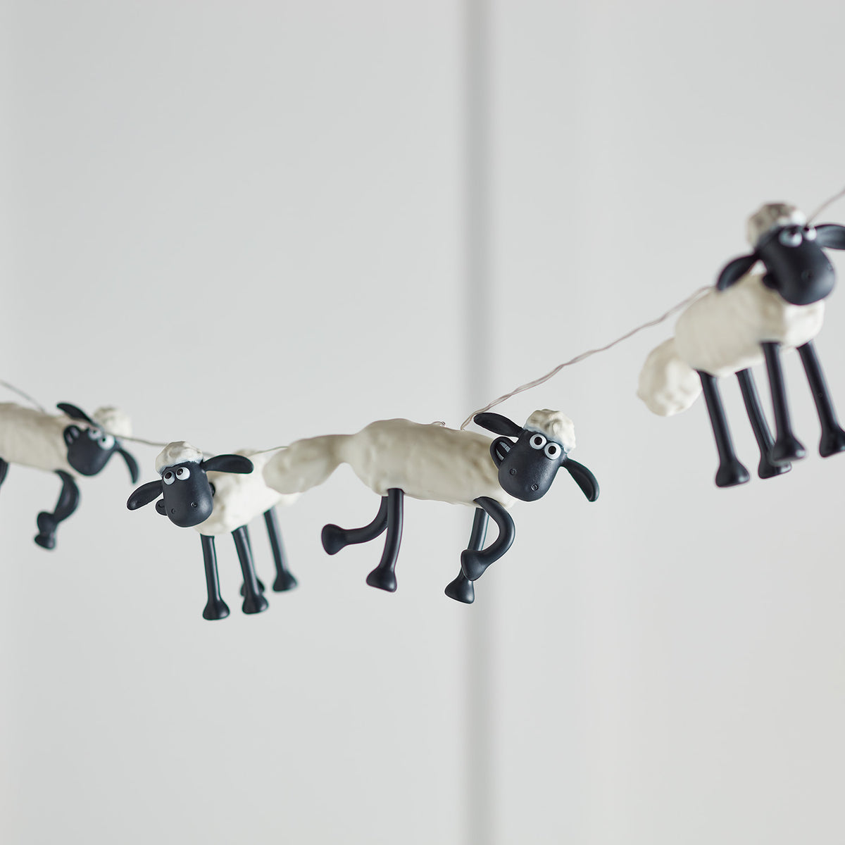 Mehrere Shaun the Sheep Figuren der Lichterkette ohne Beleuchtung vor hellem Hintergrund