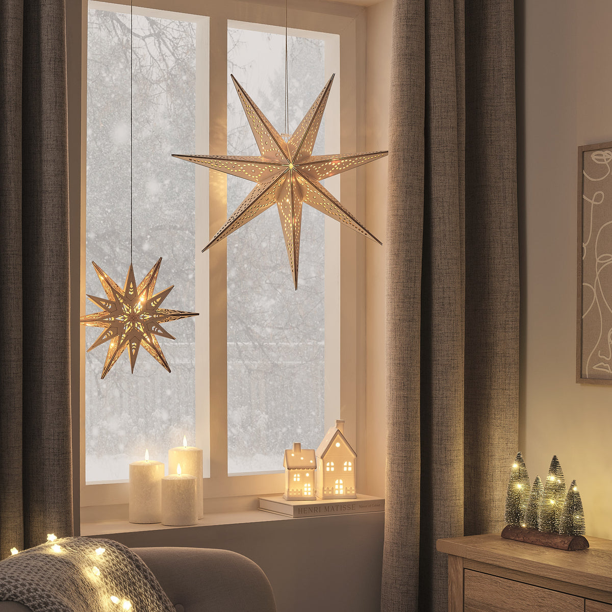 Gemütliche Fensterdekoration mit LED-Holzstern, Kerzen, beleuchteten Häuschen und Mini-Weihnachtsbäumen