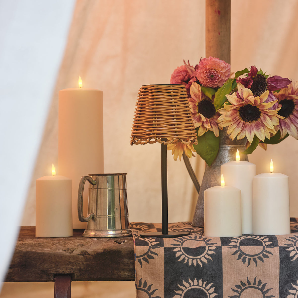 Solar-Tischlampe im Bambus-Look auf Holztisch mit Kerzen, Blumen und Metallkrug