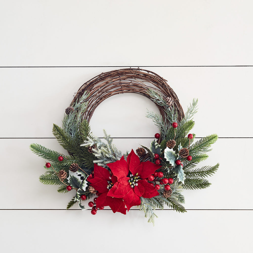 Halbkranz aus braunen Zweigen mit roten Weihnachtssternen, grünen Tannenzweigen und roten Beeren