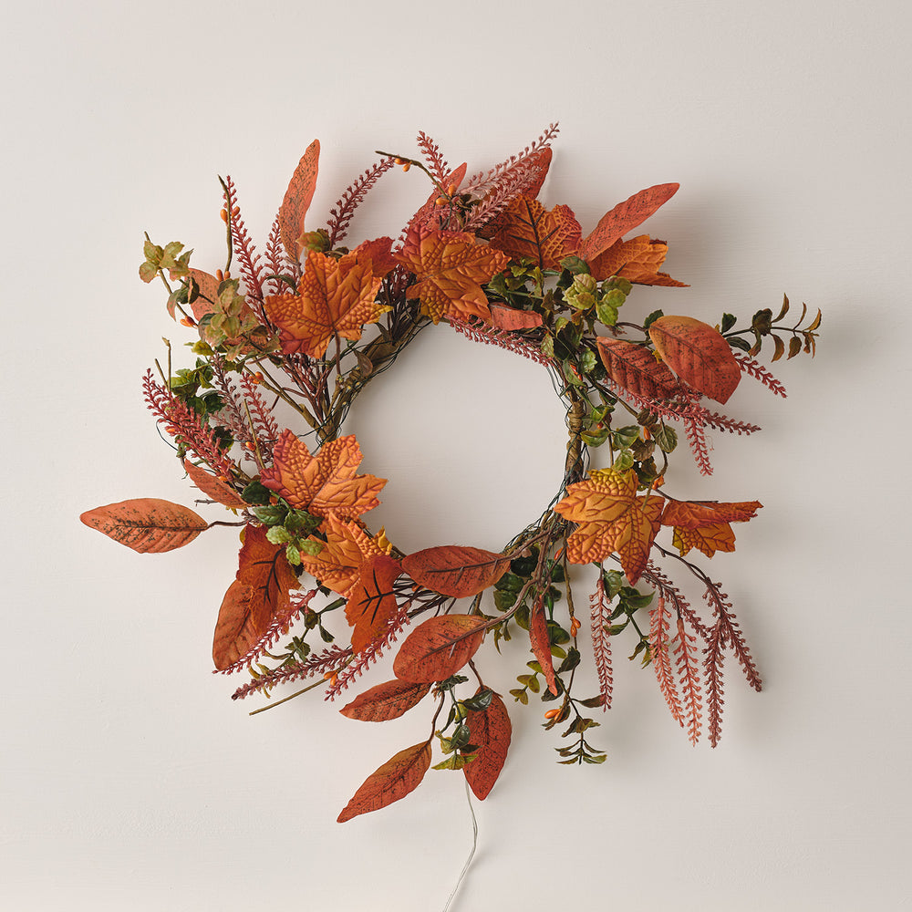 Herbstkranz mit orangefarbenen Ahornblättern und grünen Blättern von oben fotografiert
