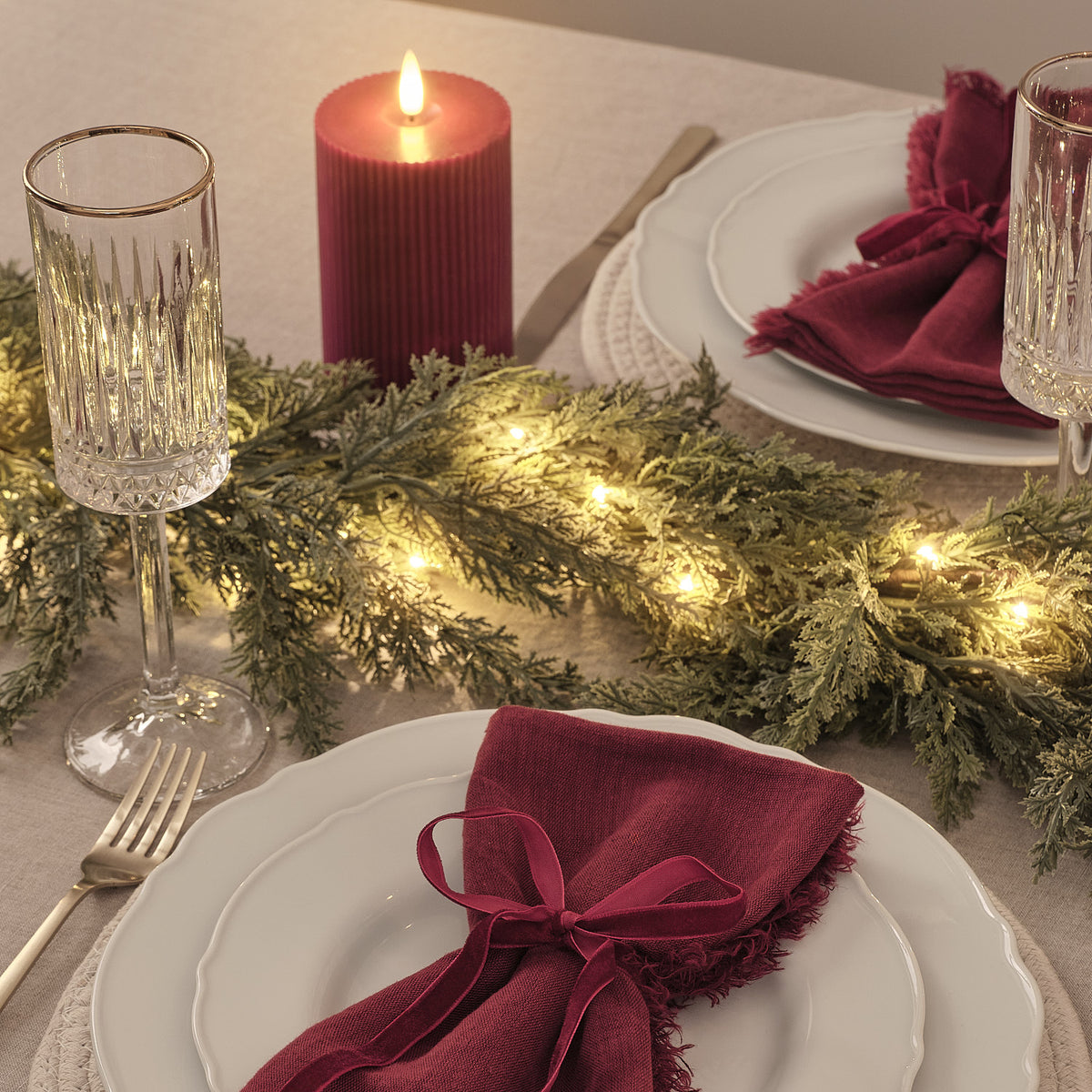 Weihnachtsgirlande mit warmweißen LEDs auf festlich gedecktem Esstisch mit rotem Stoff