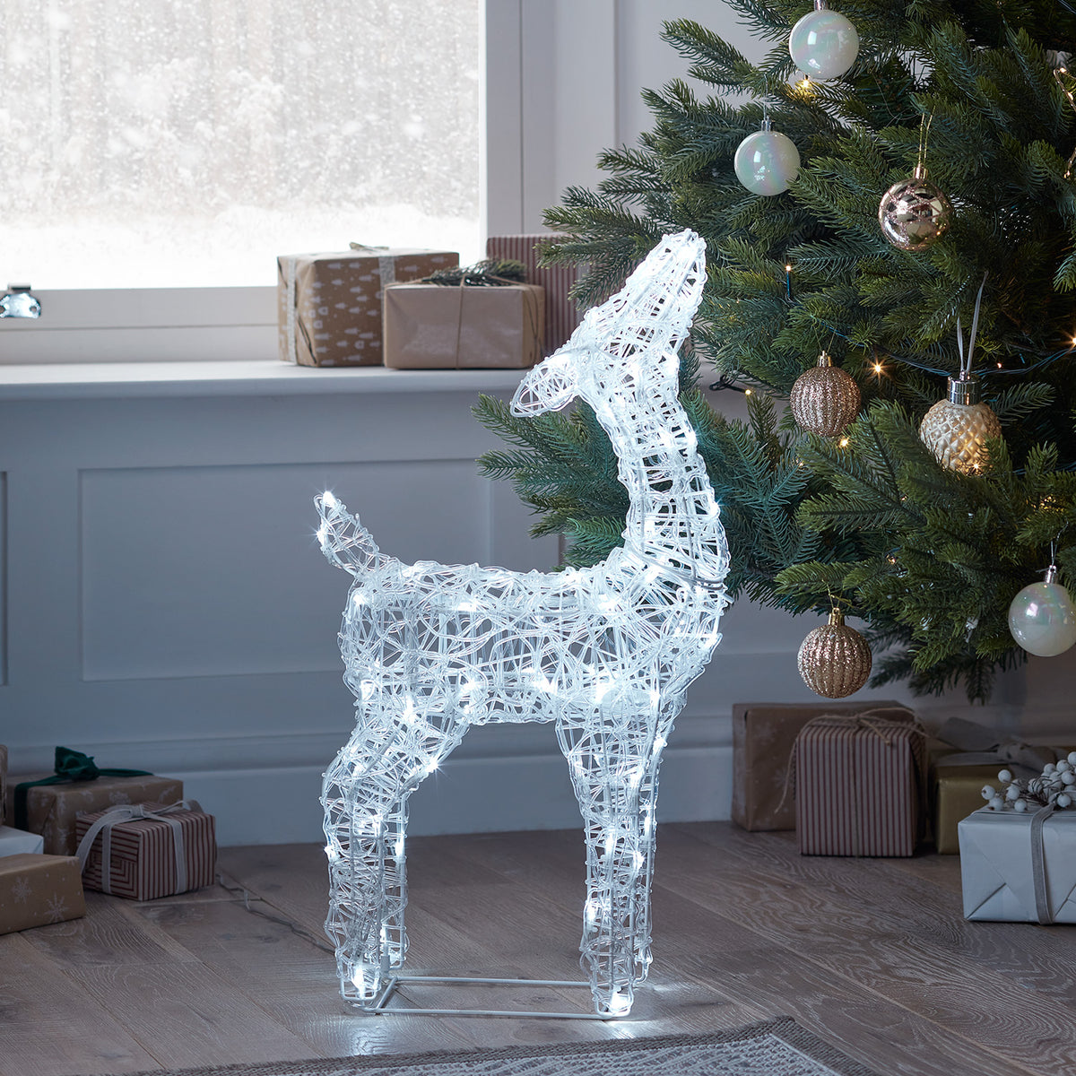 Leuchtende Acryl-Rentier Rehkitz im Wohnzimmer vor Fenster mit Weihnachtsbaum und Geschenken