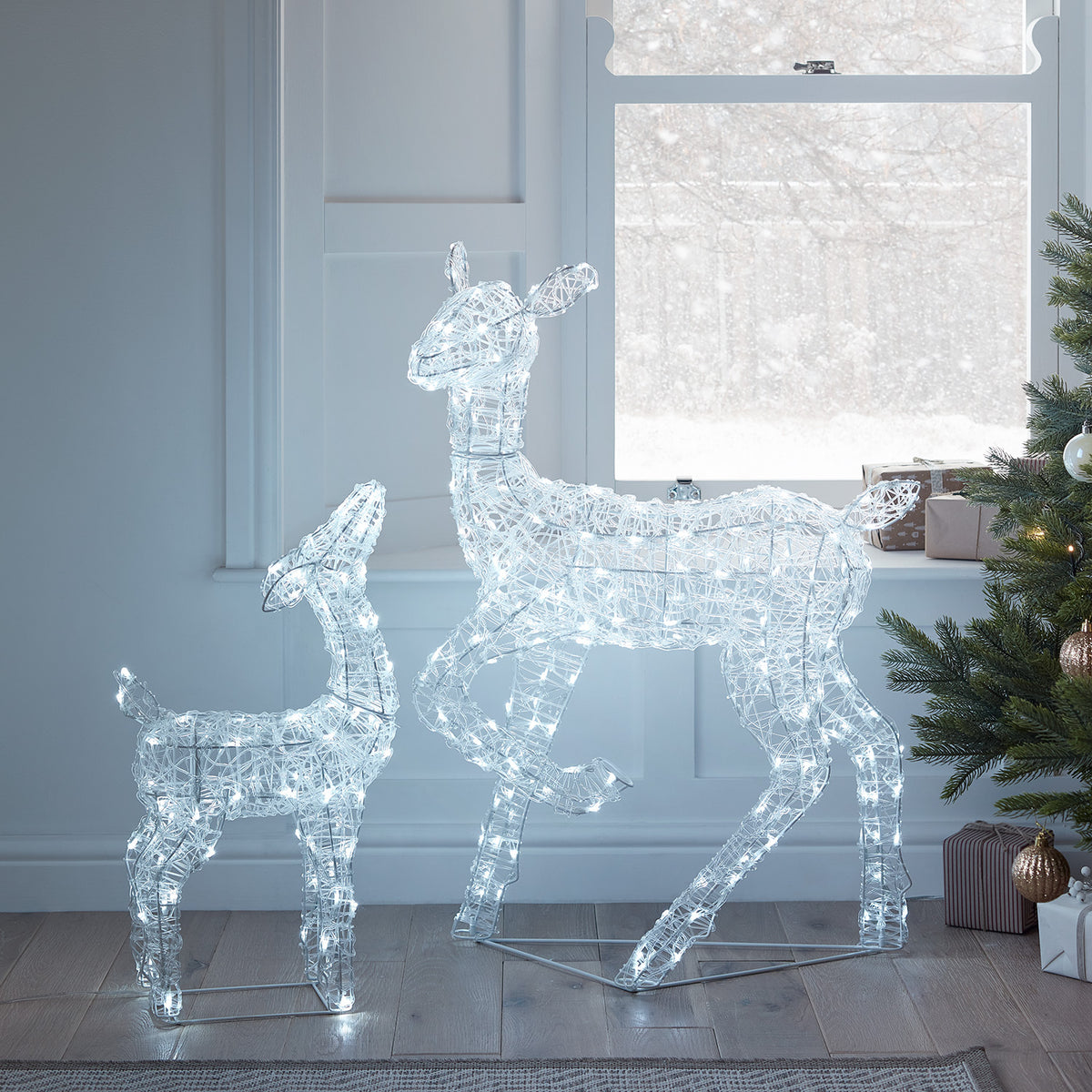 Leuchtende Acryl-Rentiere Hirschkuh und Rehkitz im Wohnzimmer vor Fenster mit Schnee