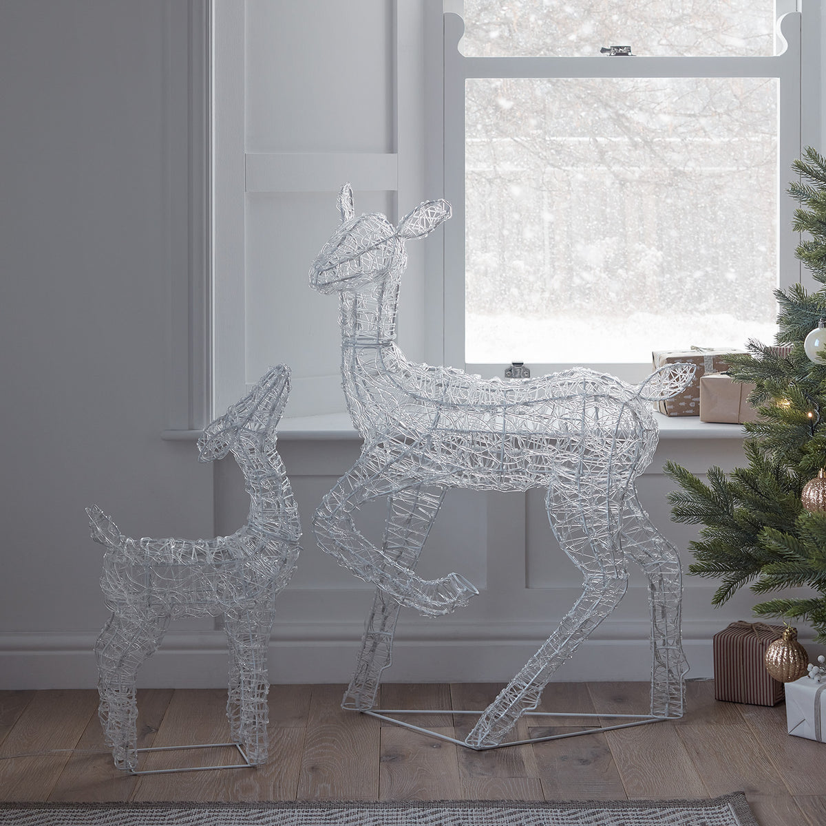 Leuchtende Acryl-Rentier Hirschkuh im Wohnzimmer vor Fenster mit Weihnachtsbaum und Geschenken