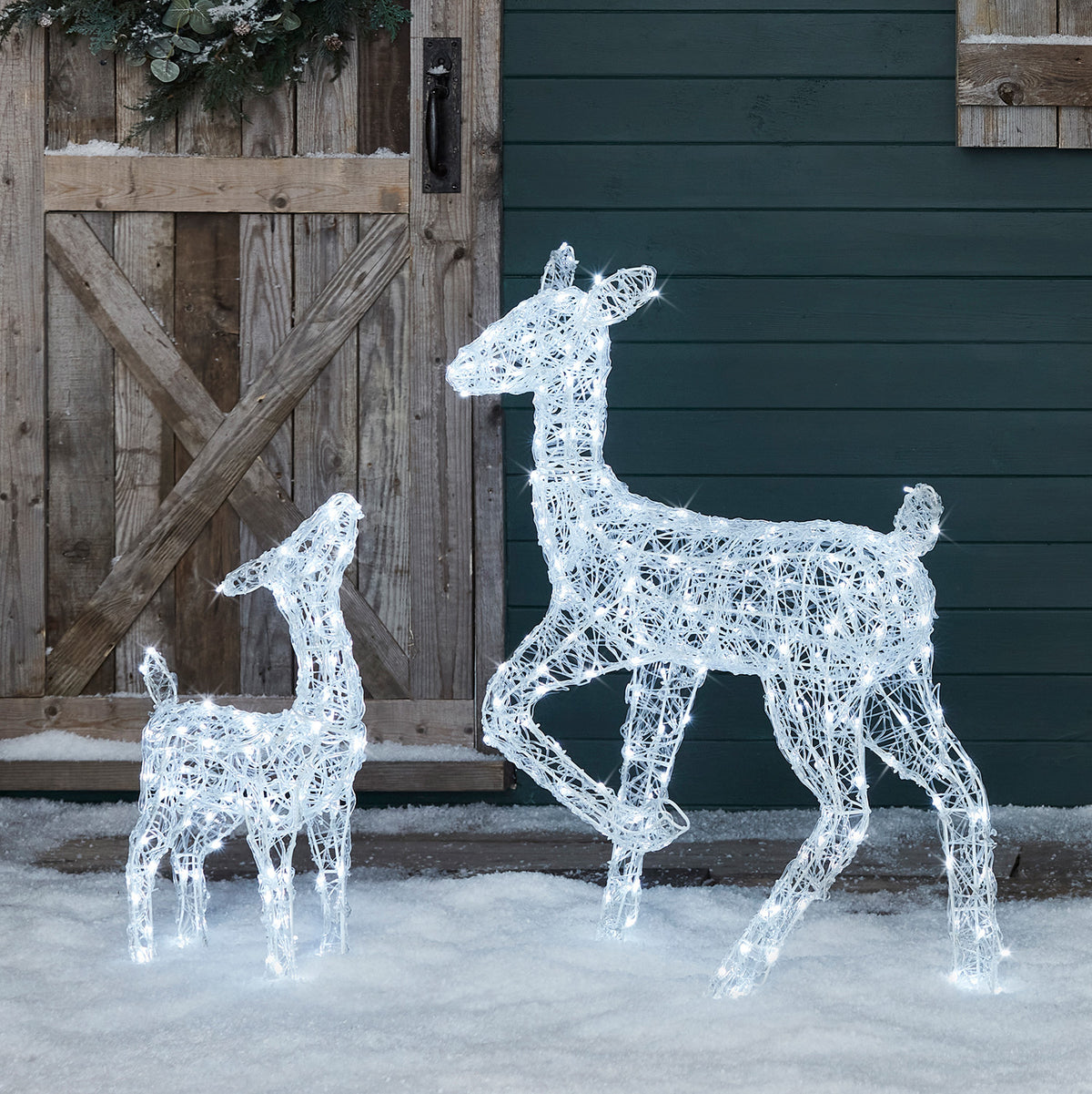 Leuchtende Acryl-Solar-LED-Rentiere Hirschkuh und Rehkitz im Schnee vor Holztür