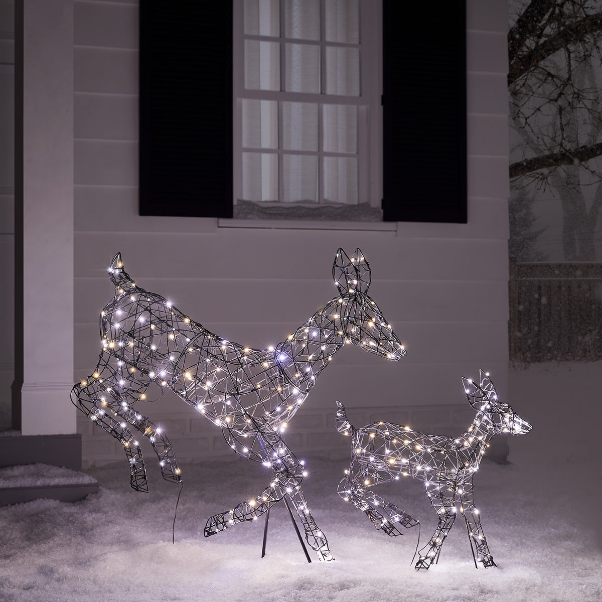 Rattan-Optik Hirschkuh und Rehkitz mit warmweißen LEDs vor Hausfassade im Schnee
