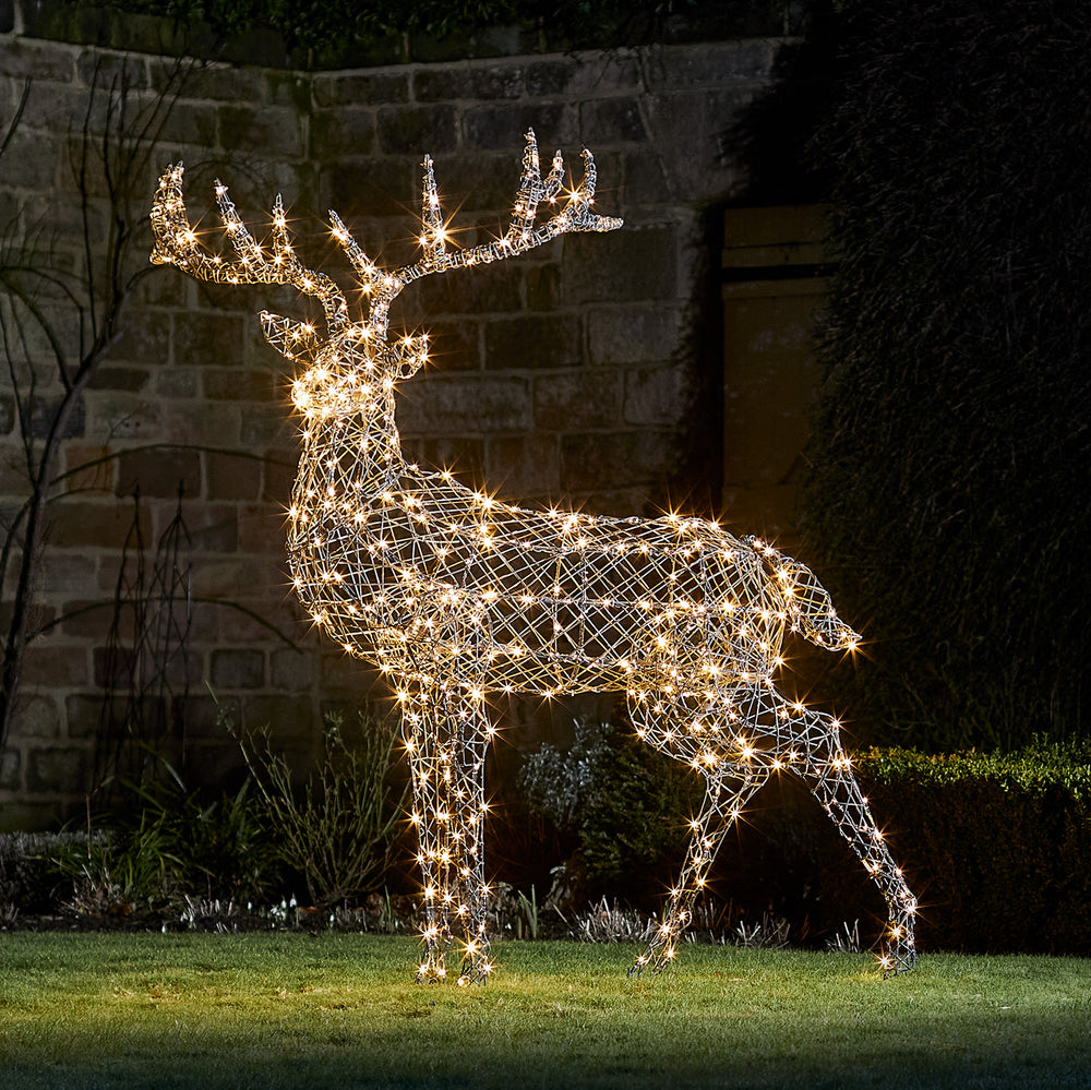 Solar-LED-Rentier in grauer Rattan-Optik mit warmweiß leuchtenden LEDs im Garten bei Nacht
