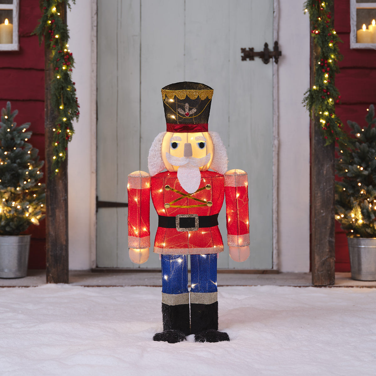 Nussknacker-Figur mit warmweißen LEDs vor Haustür mit Weihnachtsdeko und Schnee