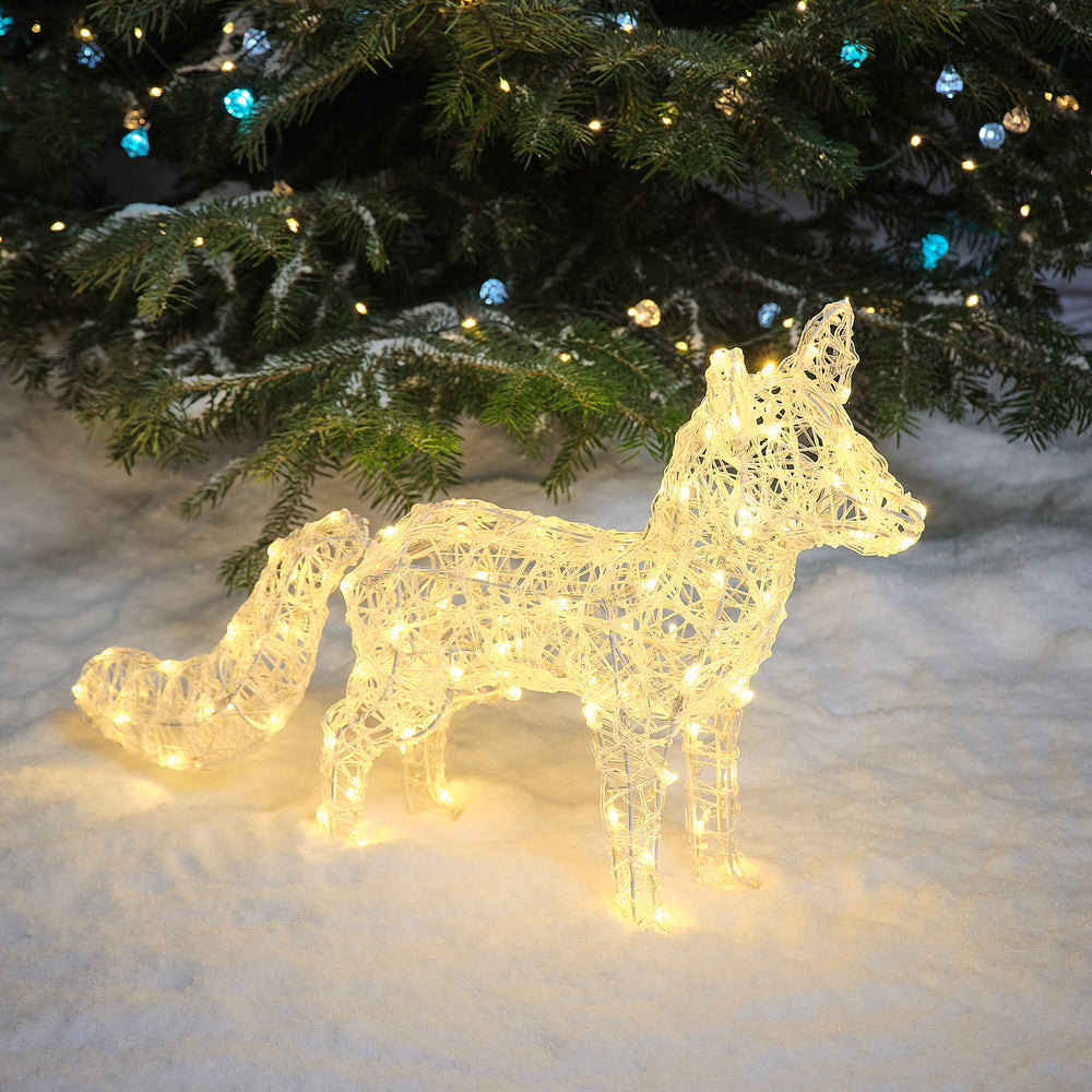 Leuchtender LED Acryl Polarfuchs in warmweißem Licht im Schnee vor Tannenzweigen