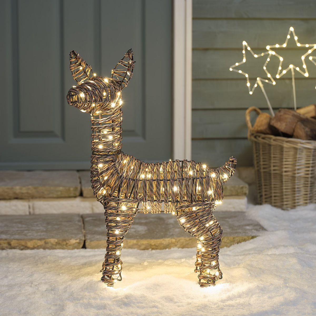 Pateley Bicolor LED-Rehkitz aus Rattan mit 110 LEDs in Warmweiß vor dem Haus