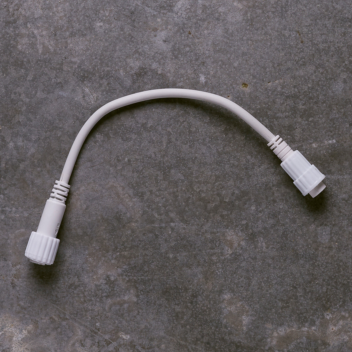 Weißes Pro Connect IP44-zu-IP67-Konverterkabel mit zwei Steckverbindern auf grauem Untergrund