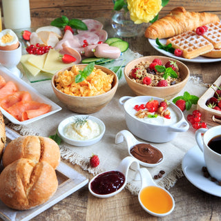 Breakfast spread with various foods including waffles, fruits, and coffee on a wooden table.