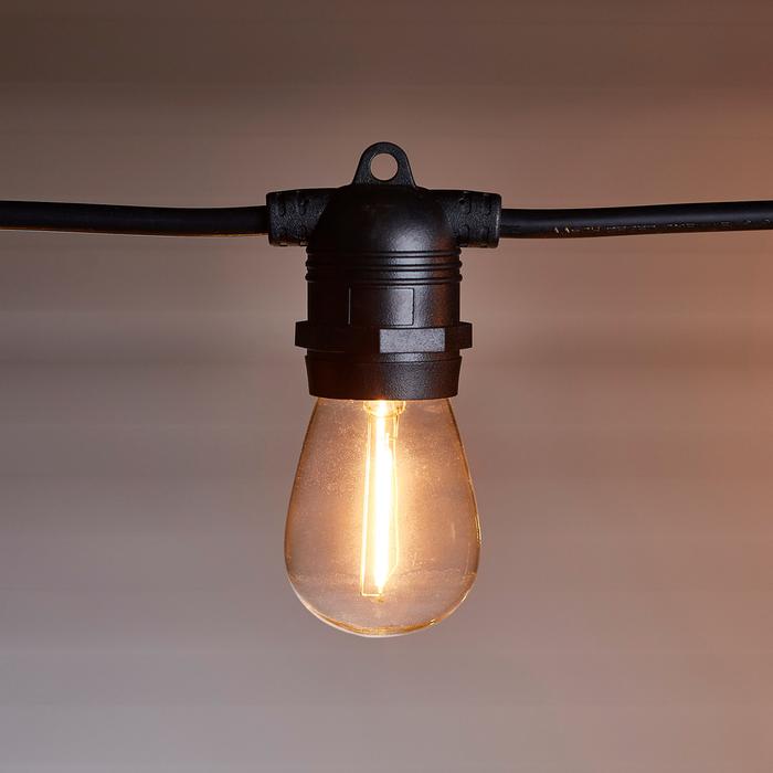 Lichterkette mit mehreren leuchtenden Glühbirnen an weißer Decke montiert