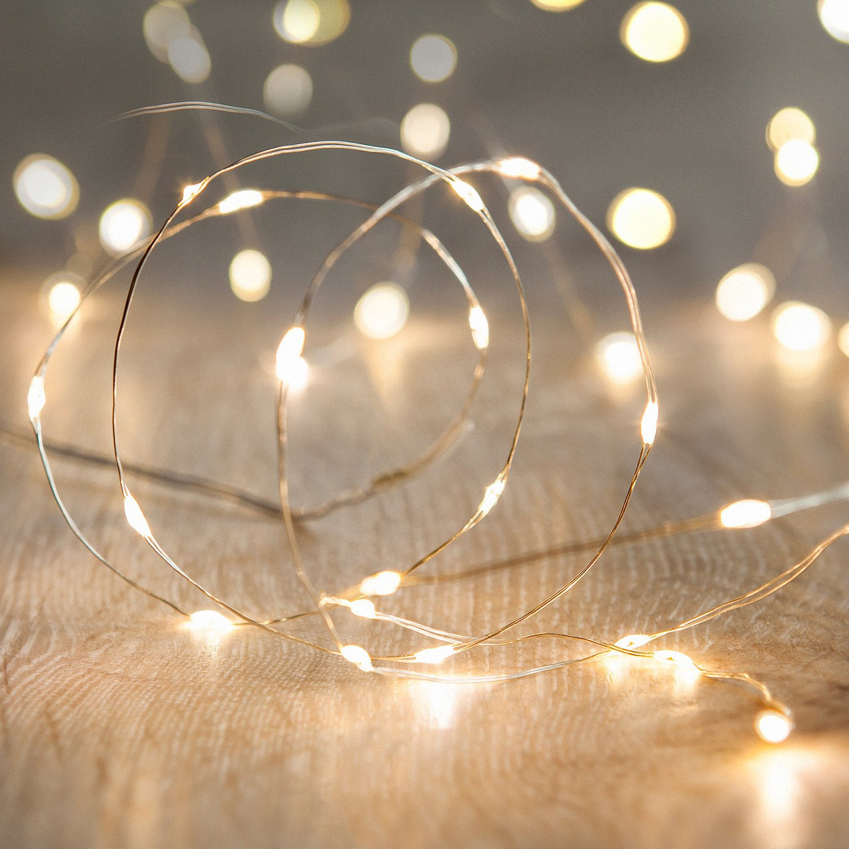 Nahaufnahme der warmweißen Micro Lichterkette auf hellem Holz mit leuchtenden LEDs